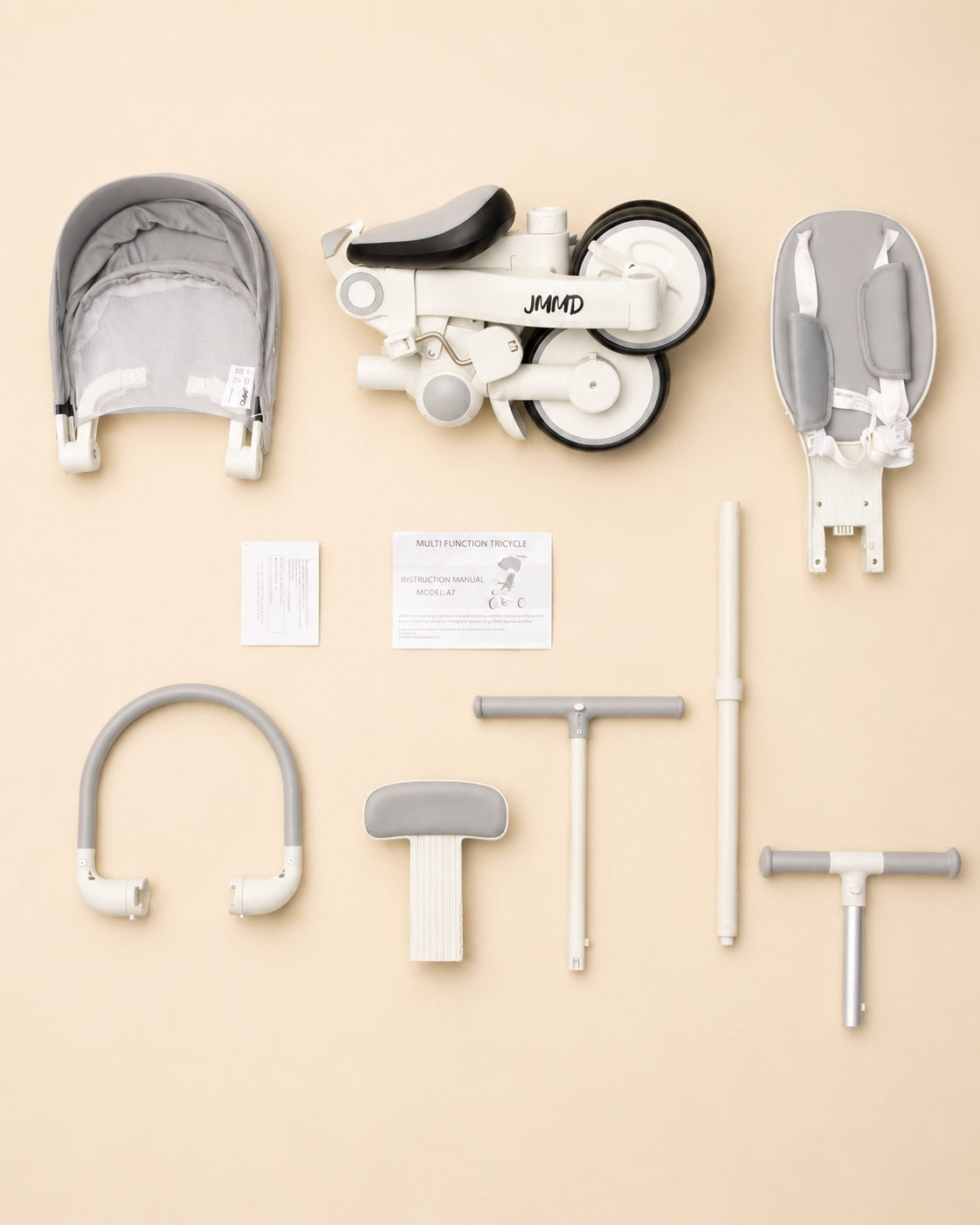 JMMD A7 kids trike components and accessories arranged in a beige studio flat lay