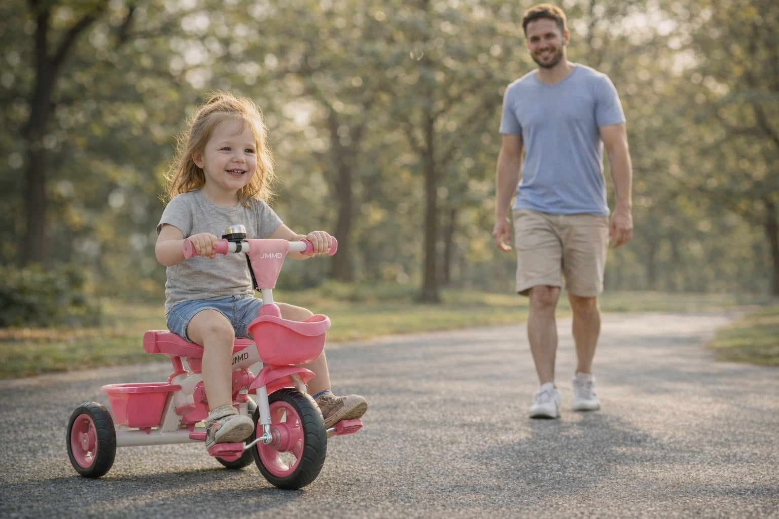 Toddler riding JMMD B31 tricycle independently outdoors while parent walking behind