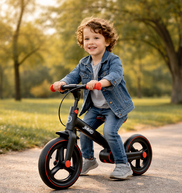 Toddler boy riding JMMD balance bike outdoors in park, enjoying smooth and stable ride