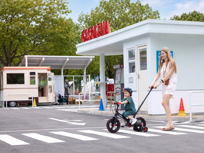 Mother guiding a child riding the JMMD S900 kids trike at an outdoor play area