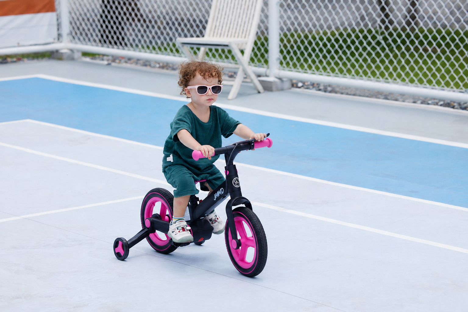 Child riding the JMMD S900 pink kids bike on an outdoor sports court