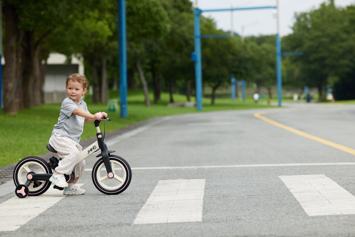 Toddler riding a JMMD kids tricycle on a quiet park road with open outdoor space